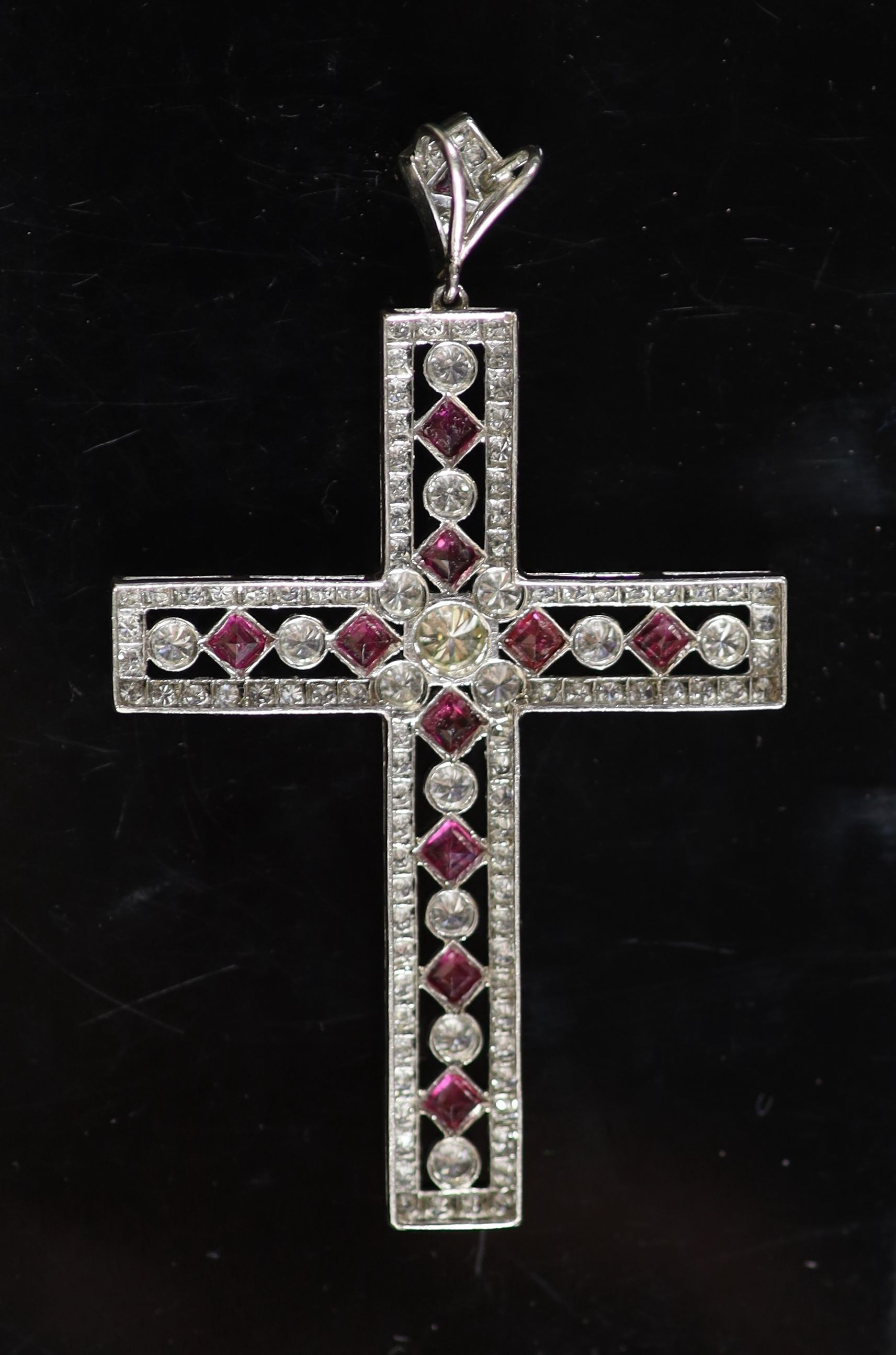 A modern pierced white gold, ruby and diamond cross pendant